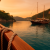 Traditional wooden gulet anchored in a calm bay near Göcek at sunset with pine-covered cliffs and orange sky reflection